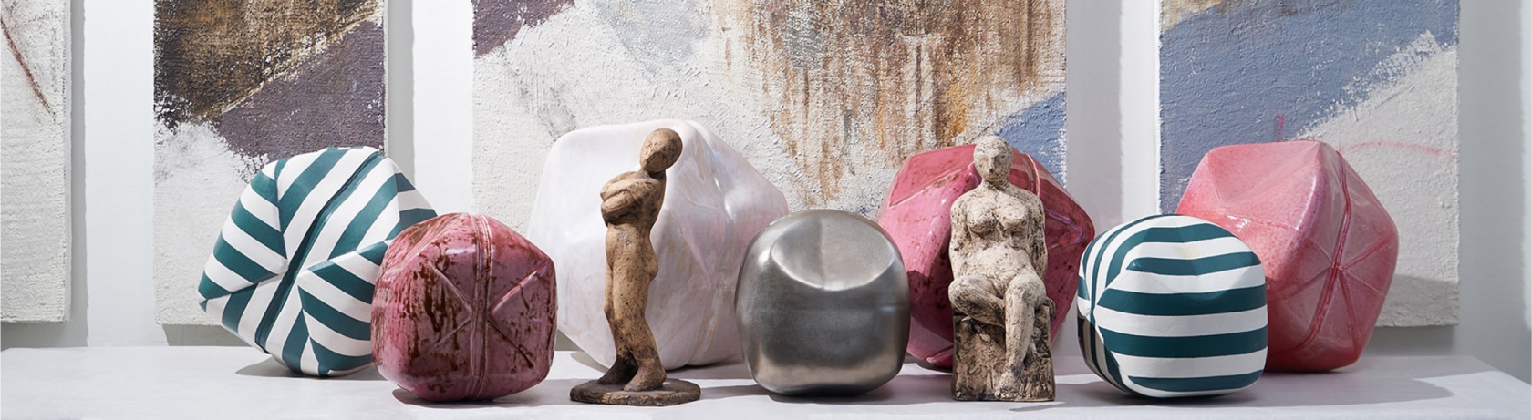 Ceramic forms and figures in front of large paintings