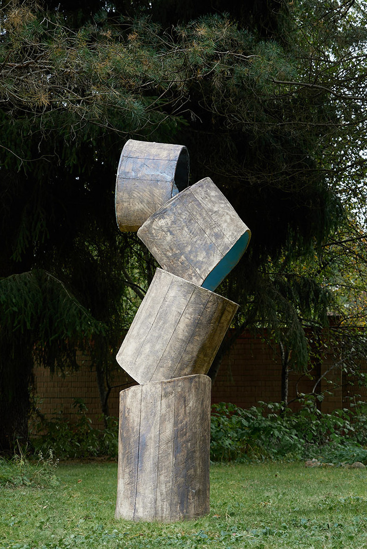 Two stacked cylinder sculptures in a garden