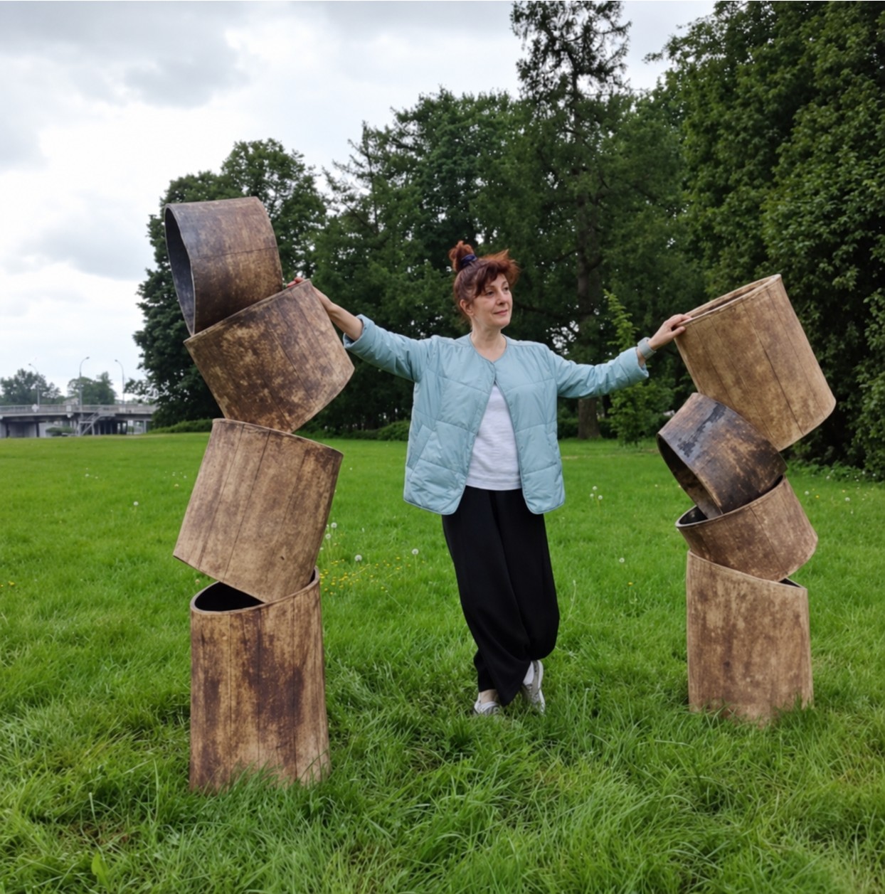 Natalia Babayan accanto alle sue sculture in ceramica di cilindri sovrapposti in un parco