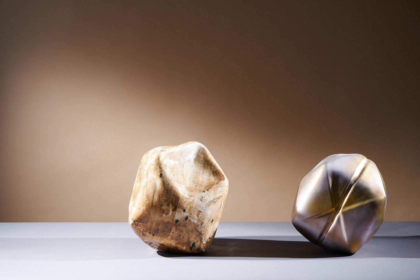 Two faceted ceramic forms: glazed stone and silver